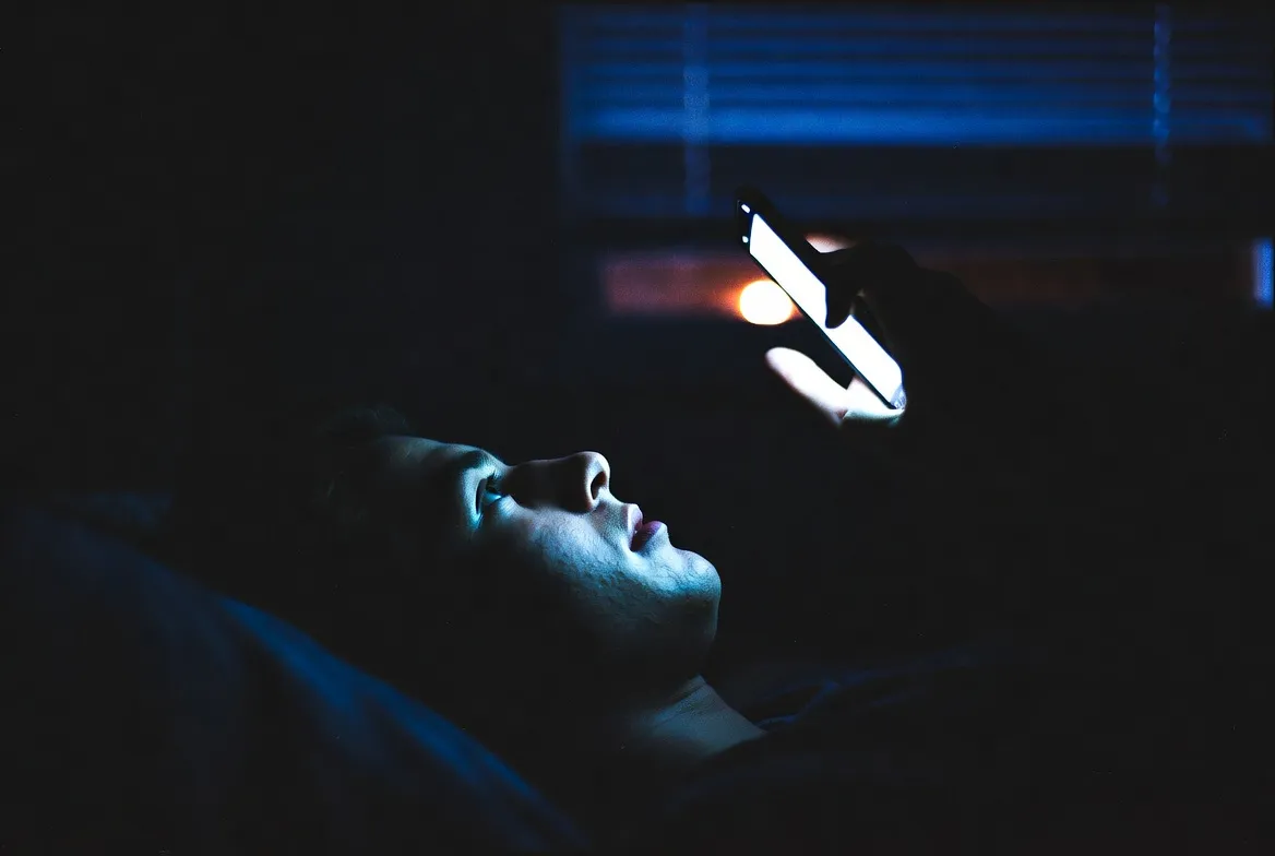 Persona sola de madrugada mirando el teléfono, atrapada en el mismo patrón